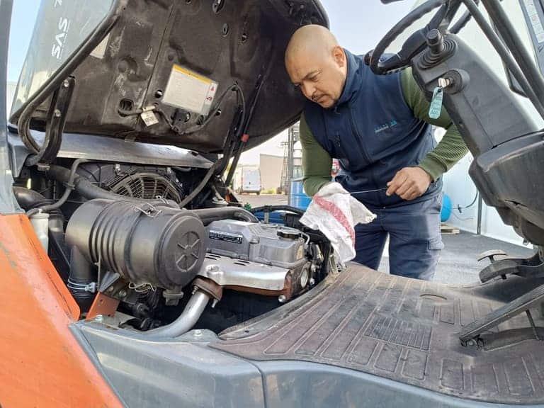 Photo d'un technicien qui réalise un entretien - maintenance sur le moteur d'un chariot élévateur