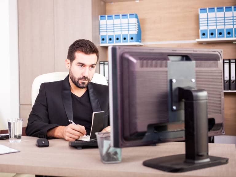 Photo d'un homme qui réalise un devis devant son ordinateur